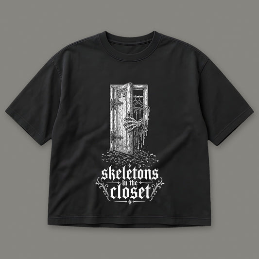 Skeletons in the Closet Women's Boxy Tee in black by Trauma Dump, skeleton hand in a closet door tattoo-style gothic graphic (Black, white ink)