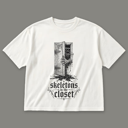 Skeletons in the Closet Women's Boxy Tee in white by Trauma Dump, skeleton hand in a closet door tattoo-style gothic graphic in black ink