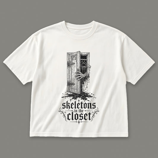 Skeletons in the Closet Women's Boxy Tee in white by Trauma Dump, skeleton hand in a closet door tattoo-style gothic graphic in black ink