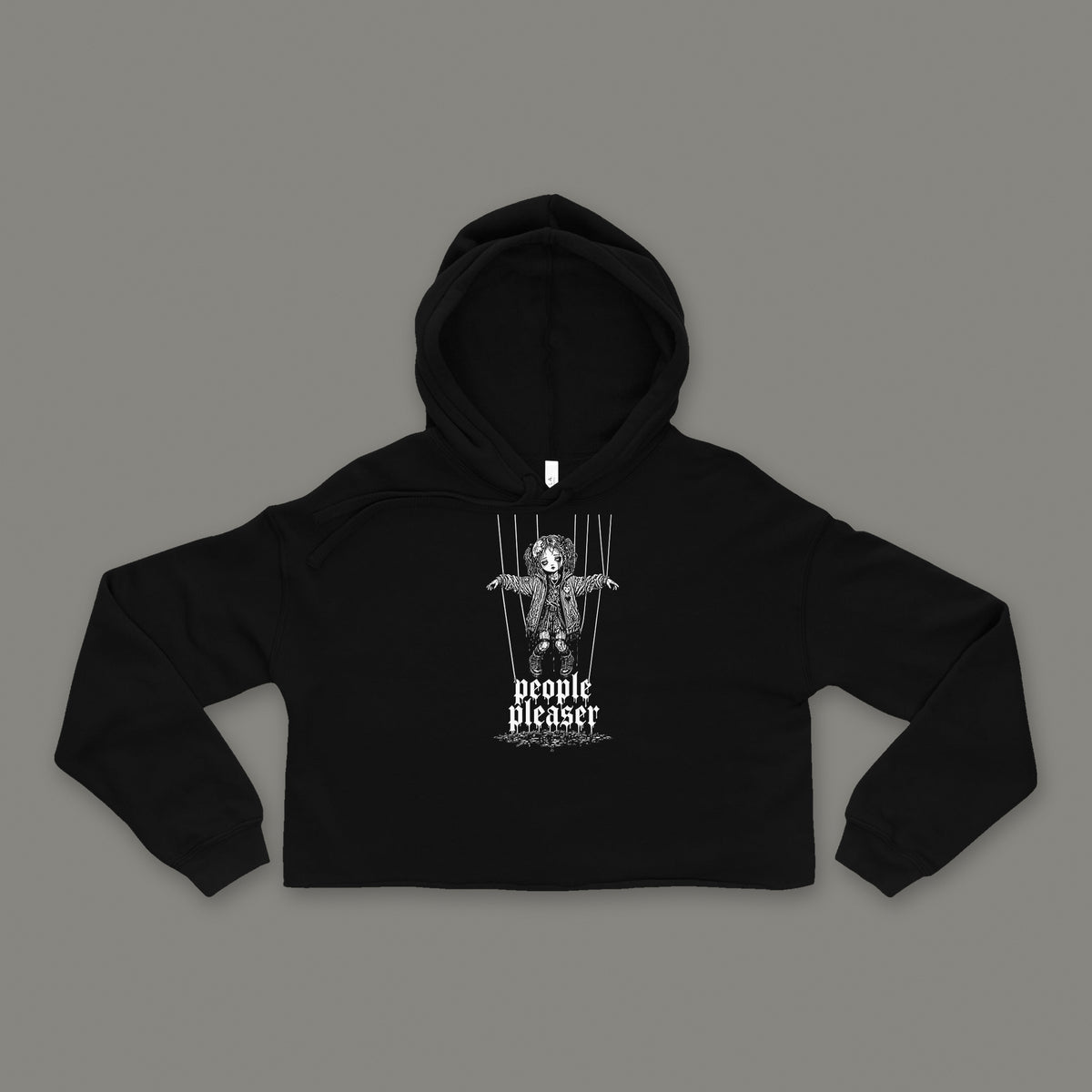 People Pleaser Cropped Hoodie by Trauma Dump, black goth cropped hoodie front with cut-strings marionette print, mockup view 3 (Black, white ink)